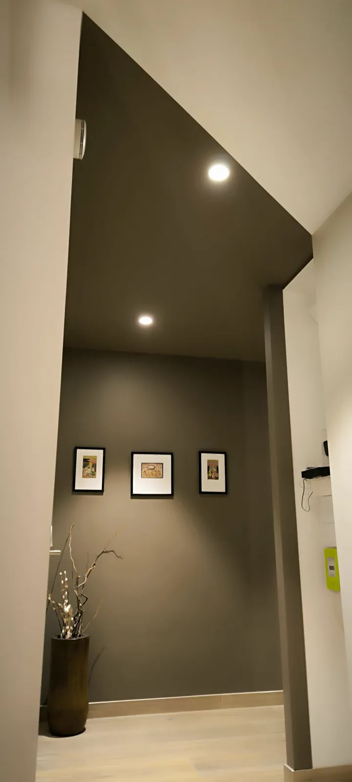 Couloir sous rampant peint en taupe et blanc, avec trois cadres