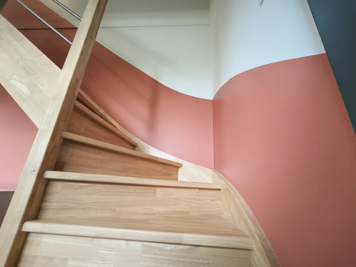 Escalier en bois avec un soubassement peint en courbes vieux rose